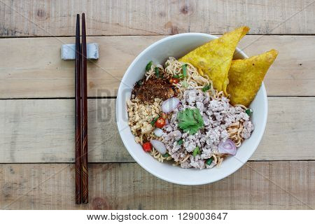 Spicy instant noodle with minced pork on wood background.Topview