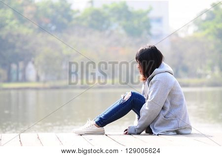 Depressed woman sitting River in the Park