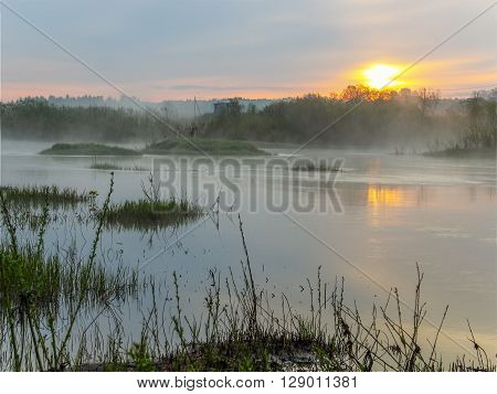 Orange rising over the river and coast covered with fog.