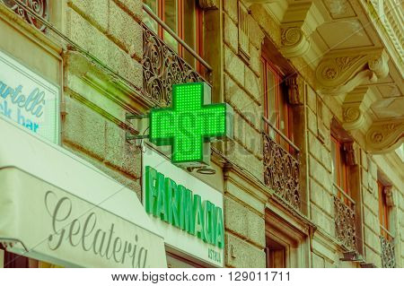 FLORENCE, ITALY - JUNE 12, 2015: Green cross, farmacia sign of medical store. Store sign in historic building, letters on green.
