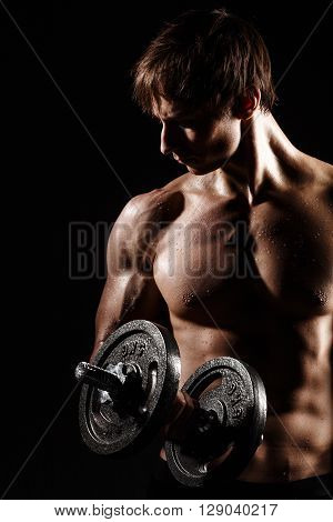 Muscular And Fit Young Bodybuilder Fitness Male Model Posing Over Black Background With Dumbbell. Pe