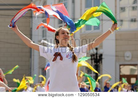 Orel Russia - May 9 2016: Celebration of 71th anniversary of the Victory Day (WWII). Girl in white dancing with colored ribbons closeup