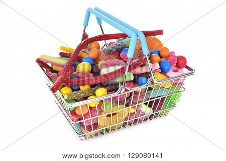 a metal shopping basket full of candies with different shapes and flavors on a white background