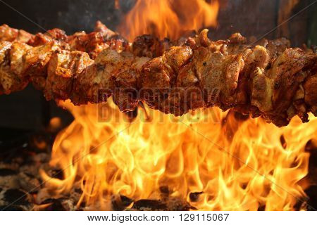 A spit roast on a grill with flames in the background