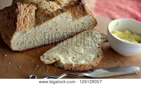 Soda Bread Loaf with buttered slice and small pot of butter.