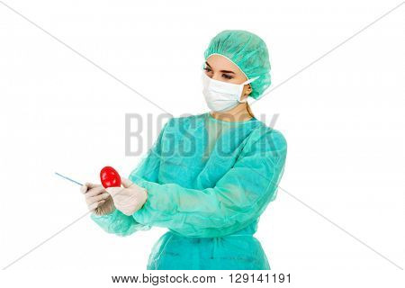 Young female cardiologist surgeron holding heart and scalpel
