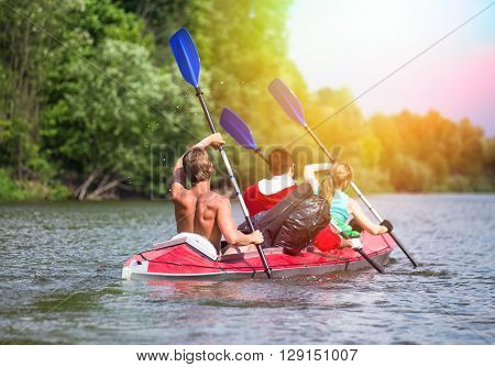 Young people are kayaking on a river in beautiful nature