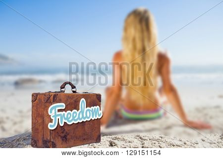 Old suitcase with the message freedom against a woman getting a tan