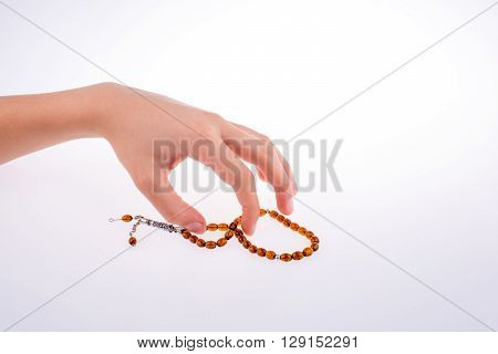 Hand holding a tespih on a white background