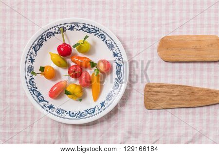 Sweet dessert in fruit shape on dish with small paddle on pink napery background