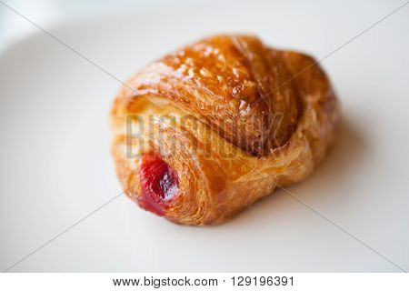 Croissant stuffed with jam on a white plate