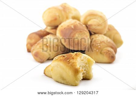 Fresh Serbian pastry rolls with cheese and sesame, kifla kiflice, one bitten, isolated on white background