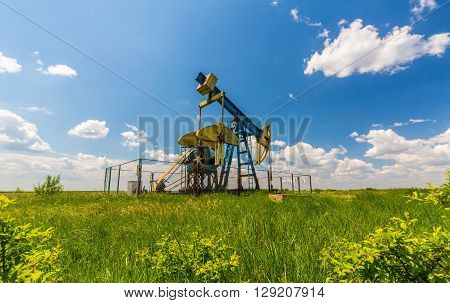 Oil and gas well profiled on blue sky with cumulus clouds