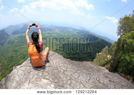 young woman hiker use smartphone taking photo on seaside mountain top