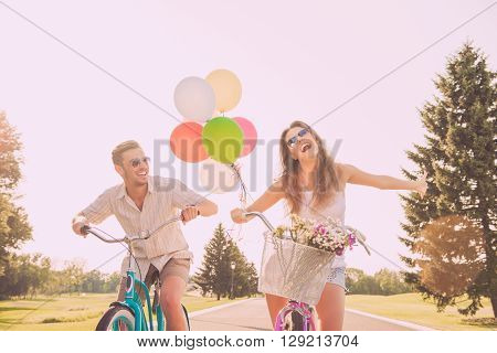 Portrait Of Heerful Young Woman And Her Boyfriend Having Walk With Bicycles