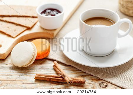 sweet breakfast with coffee and tasty multicolored macaroons on wooden table