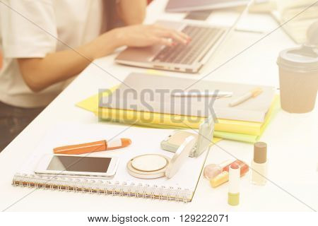 Closeup picture of cosmetics represented among exercise-books, documents and university, colleage or school things for studying. Toned image.