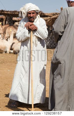 DARAW, EGYPT - FEBRUARY 6, 2016: Portrait of elderly camel salesman with stick at Camel market.