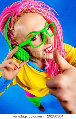 Ultra trendy DJ party girl in bright clothes, headphones and with bright dreadlocks. Disco, party. Show business. Bright fashion.