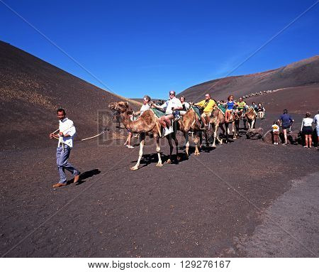 LANZAROTE, SPAIN - MARCH 3, 1998 - Tourists taking a camel ride through Timanfaya National Park Lanzarote Canary Islands Spain, March 3, 1998.
