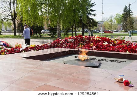 PETROZAVODSK, RUSSIA - MAY 10TH, 2016: Eternal fire against flowers after May 9th day of great victory, celebration of the victory in the second world war