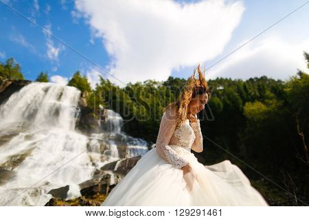 bride posing near the norvegian waterfall with blue skies