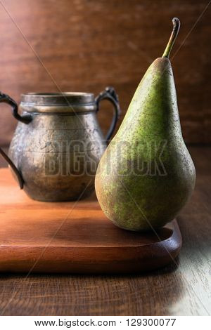 Pear and bronze dish on wooden cutting board