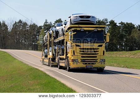 SALO, FINLAND - MAY 8, 2016: Yellow Scania R500 truck hauls a load of new cars along highway in South of Finland on a sunny day of spring.