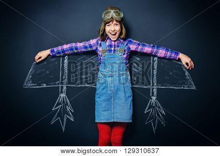 Dream flight. Cheerful girl imagines herself a pilot. Childhood. Fantasy, imagination.