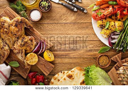 Grilled vegetables and chicken on wooden table overhead shot