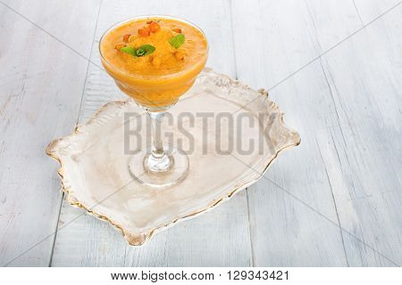 A glass of buckthorn smoothie on a  vintage tray and whight wooden background