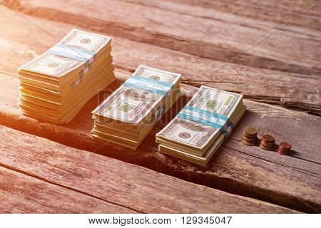 Dollar bundles near coins. Small coins and cash. Money on old wooden shelf. From rags to riches.