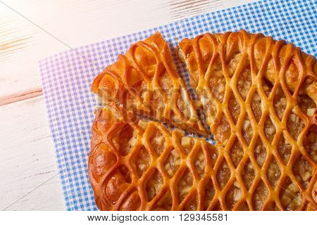 Sliced pie laying on napkin. Pie on white wooden background. Delicious pastry with fruit filling. Tasty organic meal.