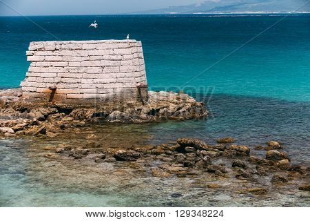 Ancient Marine Fortifications. Ruins Of Old Tower Into Mediterranean Sea In Tarifa, Spain. Tarifa Is The Most Southern Town Of Europe On The Strait Of Gibraltar
