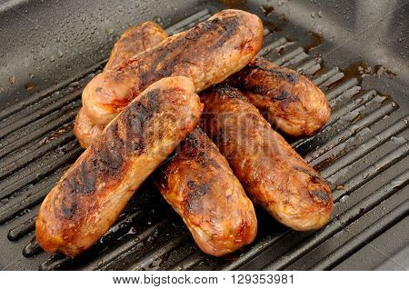 Freshly cooked pork sausages in a non stick griddle frying pan