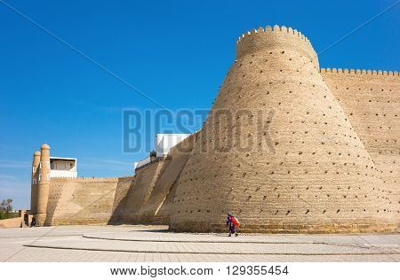 Buckara Uzbekistan - Aprilr 16 2014: The Ark fortress with a local woman walking