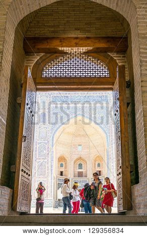Buckara Uzbekistan - Aprilr 16 2014: Local people and tourists on the entrance of the Kalon mosque