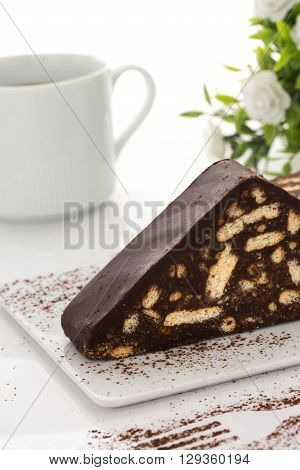Chocolate cake white coffee cup fork shape white flowers green leaves close up table top shot