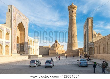 Buckara Uzbekistan - Aprilr 16 2014: Local people in the square with the Mir-i-Arab madrassah and the Kalon mosque in the background