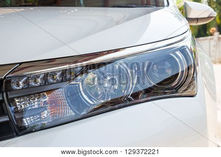 Closeup headlights of modern white car with LED daylight running lights