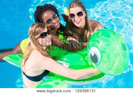 Girls in water of swimming pool with inflatable animal