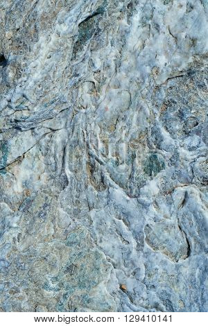 Portrait of a stone. Stone wavy texture with the influx of quartz gray white color.