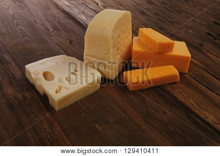 various types of fresh raw aged delicatessen cheese on wooden table cheddar edam swiss
