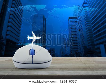 Wireless computer mouse with airplane icon on wooden table in front of map and city tower Airplane transportation concept Elements of this image furnished by NASA