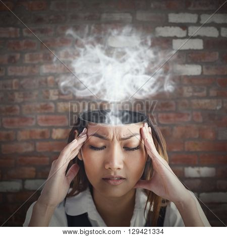 Nervous businesswoman holding her head against brick wall