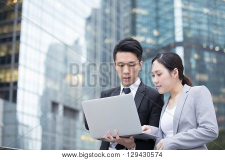 Business people team meeting with computer in front of the office building shot in Hong Kong asian