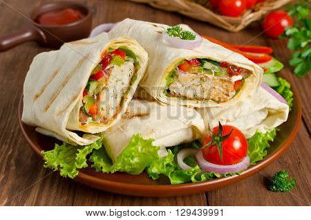 Turkish doner kebab shawarma roll with meat vegetables and pita bread on a wooden background