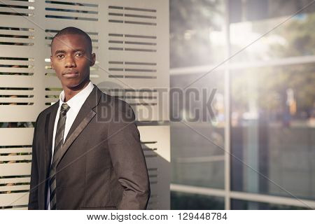 Portrait of a handsome young Businessman of African descent looking seriously at the camera while standing outside a modern office building