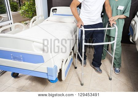 Low Section Of Nurse Helping Patient In Using Walker
