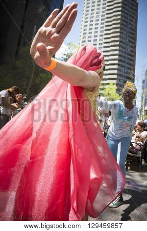 NEW YORK - APR 30 2016: A female member of NYC Bhangra and a spectator dance together in the crowd at the Holi Hai Festival of Colors in Dag Hammerskjold Plaza in New York April 30, 2016.